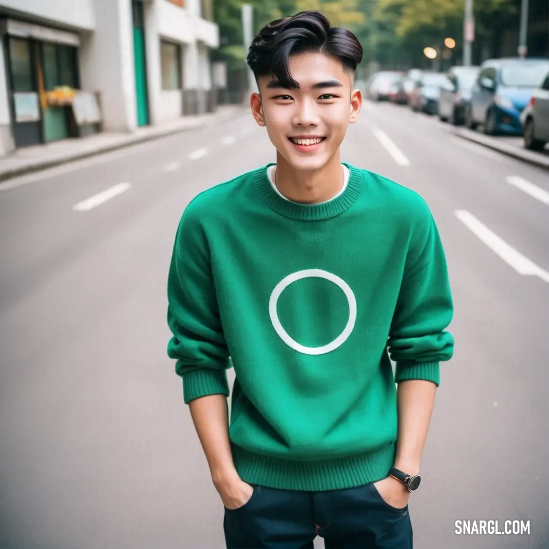 Man standing on the side of a road wearing a green sweater with a white circle on it's chest
