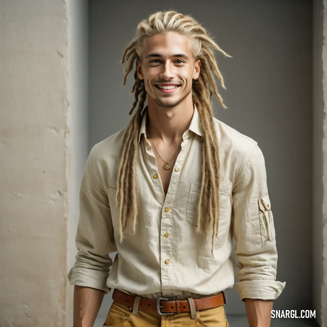 Man with dreadlocks standing in a room with a white wall and a white door behind him