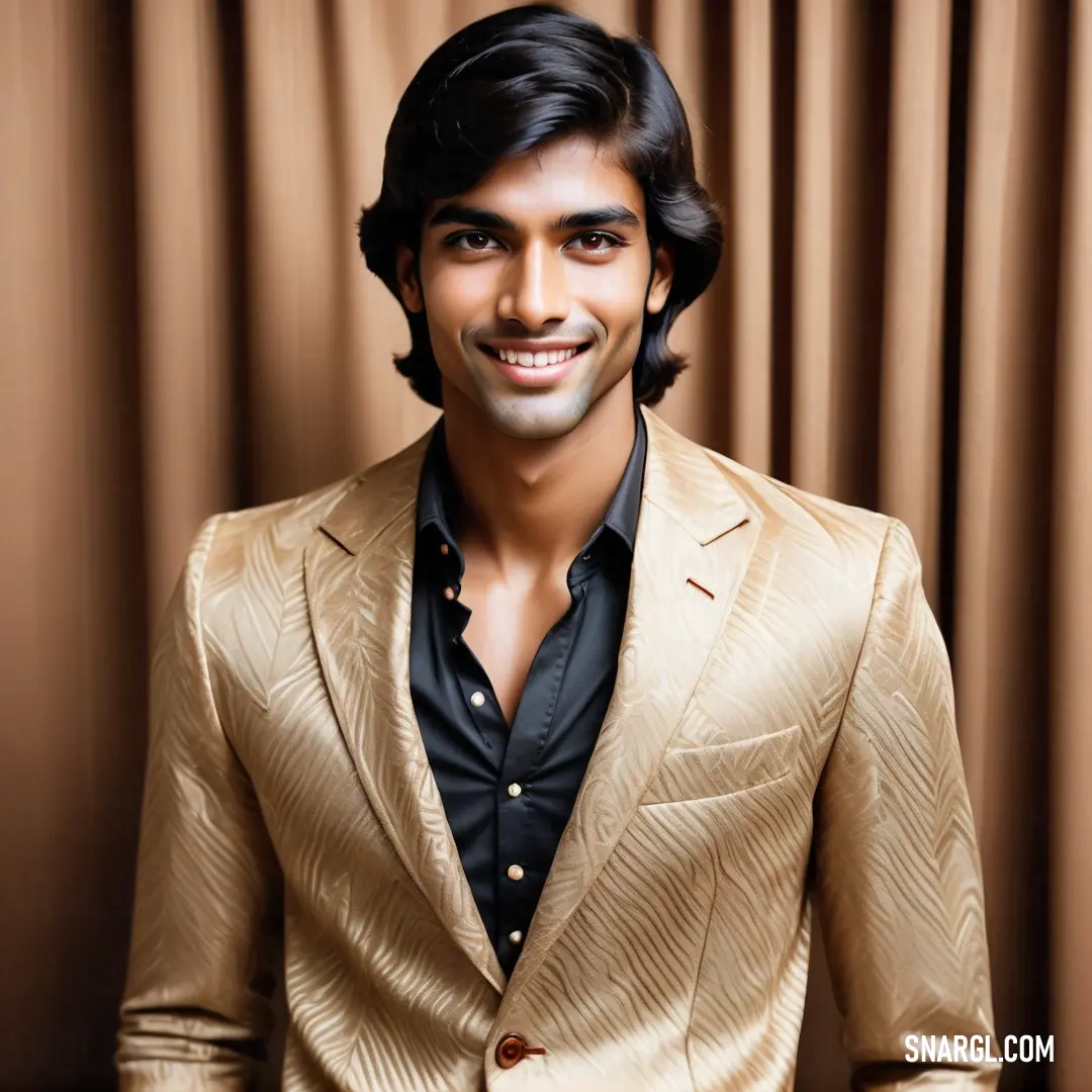 Man in a gold suit smiling for the camera with a brown curtain behind him and a black shirt underneath his shirt