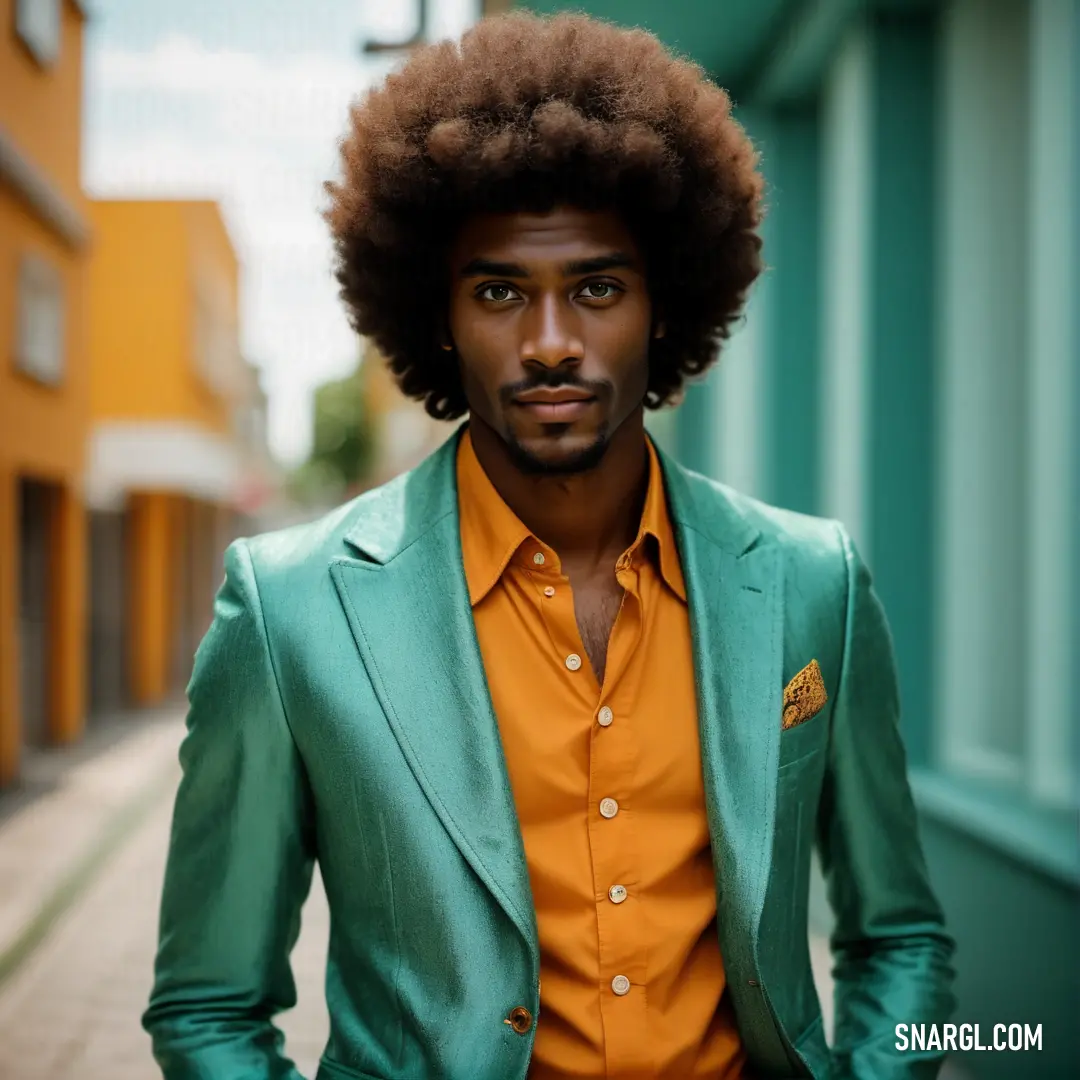 Man with an afro standing in a street with a green jacket and orange shirt on