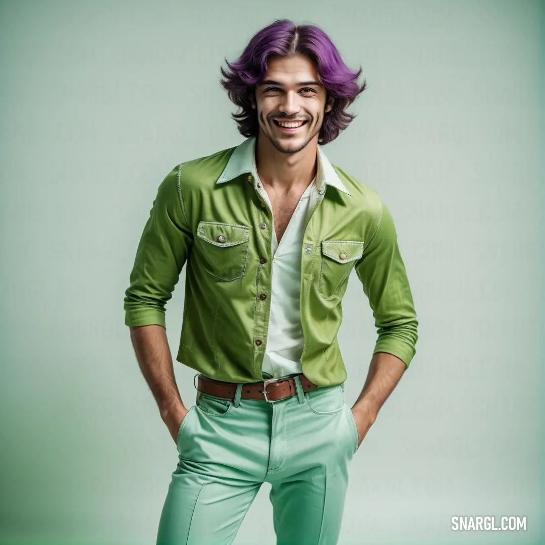 Man with purple hair and green pants posing for a picture with his hands on his hips and smiling