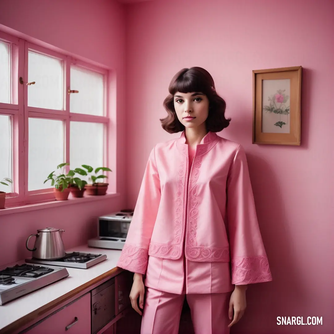 Woman in pink pajamas standing in a pink room with a pink wall and a potted plant on the counter