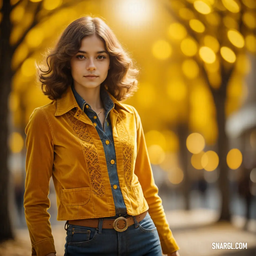 Woman standing on a sidewalk in a yellow shirt and jeans with a tree in the background