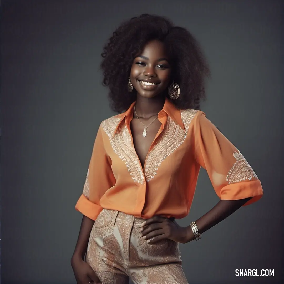 Woman with an afro is posing for a picture in a blouse and pants with a smile on her face