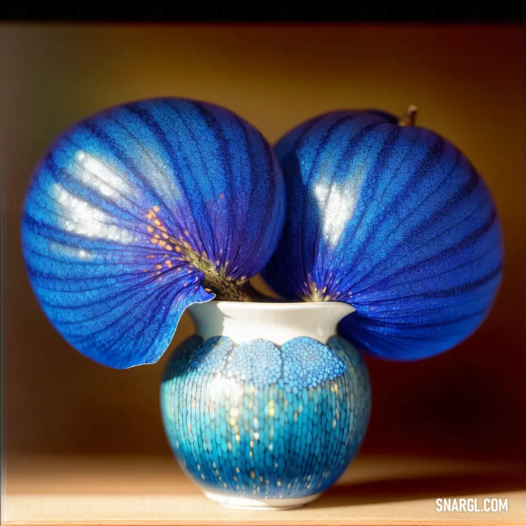 Blue vase with two blue flowers in it on a table top with a light brown background behind it