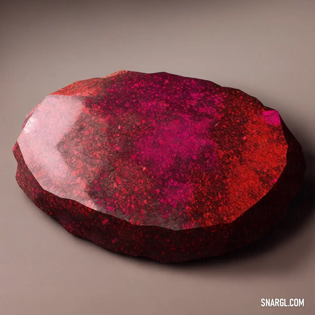 Red rock with a pink substance on it's surface on a gray background