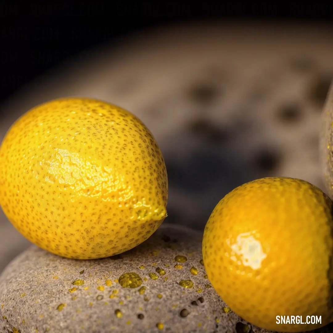 Amber color. Two lemons on top of a rock next to each other on a table top with a black background