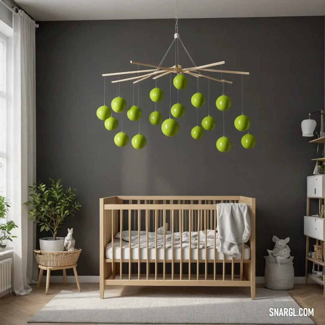 Baby crib with a green apple mobile hanging from the ceiling in a nursery room with a rug and potted plant. Example of #A4C639 color.
