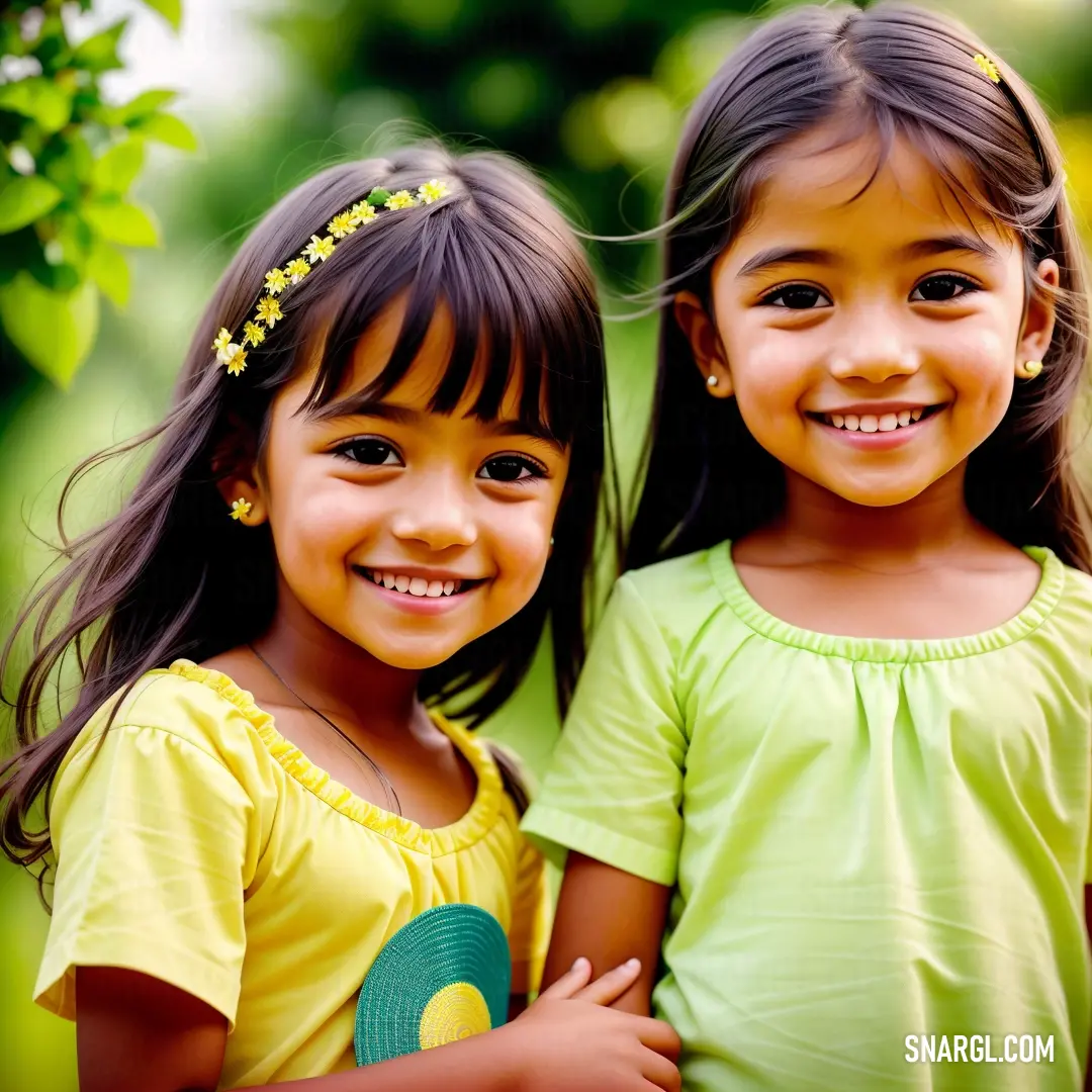 Two little girls standing next to each other smiling for the camera with their arms around each other and their heads turned