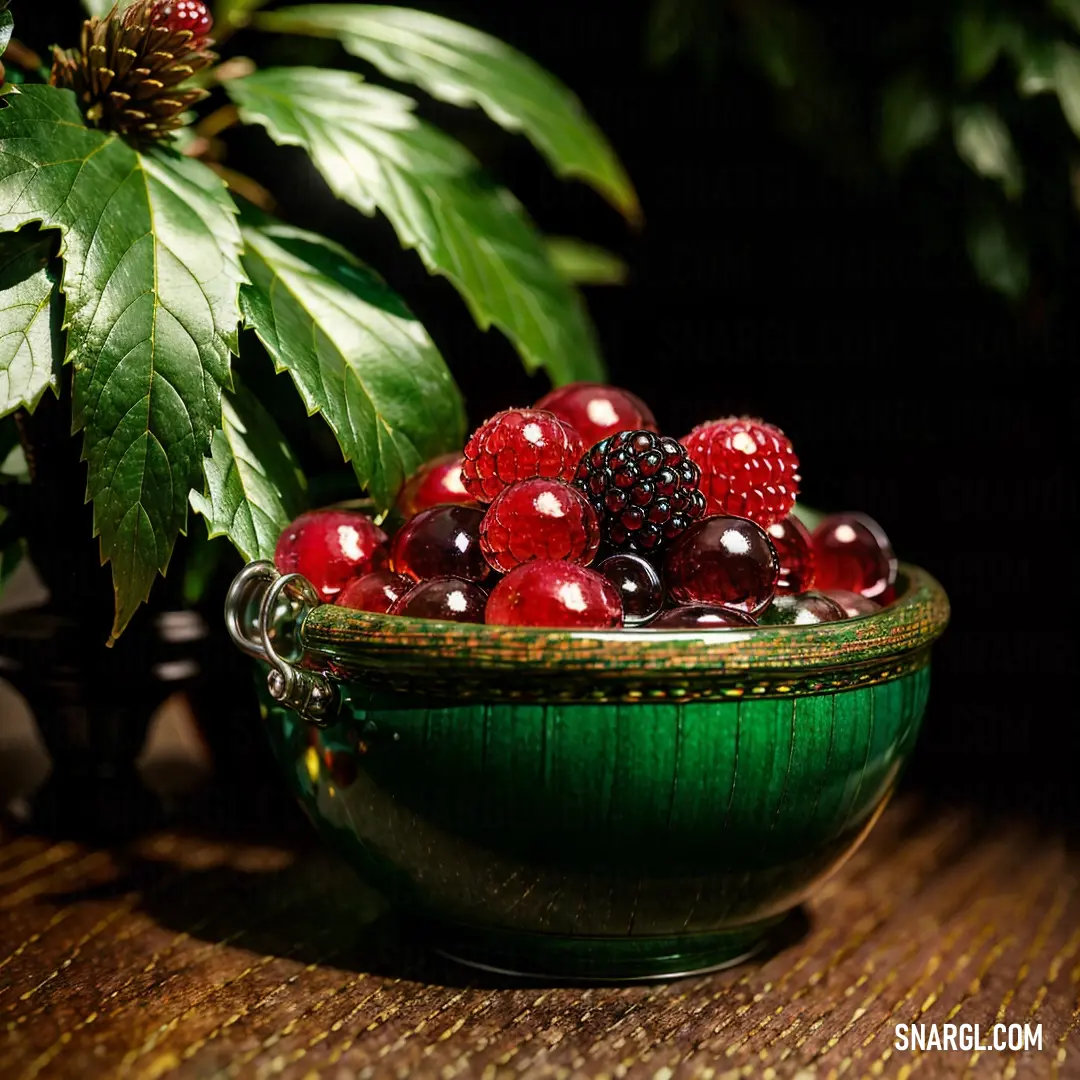 Green bowl filled with berries and berries on top of a table next to a plant with green leaves