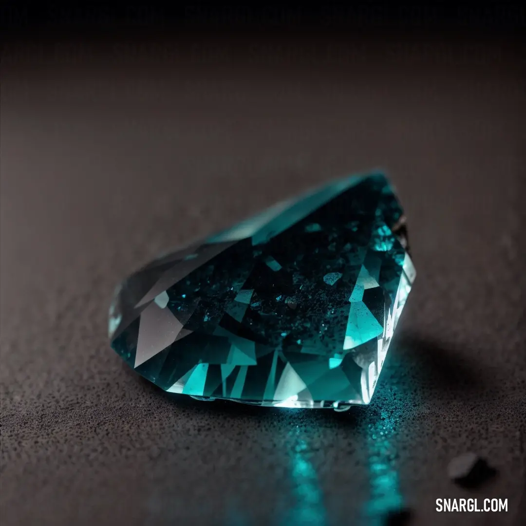 Green diamond on a table with a black background and a shadow on the ground behind it that is a bit dark