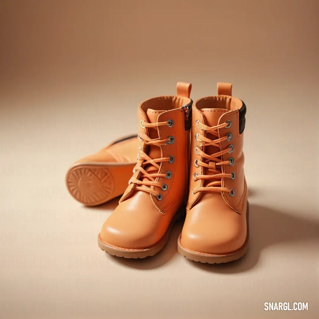 Pair of orange boots on top of a table next to a pair of brown shoes. Example of Atomic tangerine color.