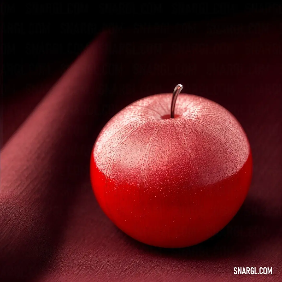 Red apple on top of a red cloth covered table cloth with a metal hook in the middle