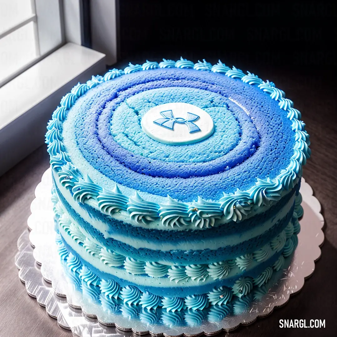 Cake with blue frosting and a star on top of it on a table next to a window