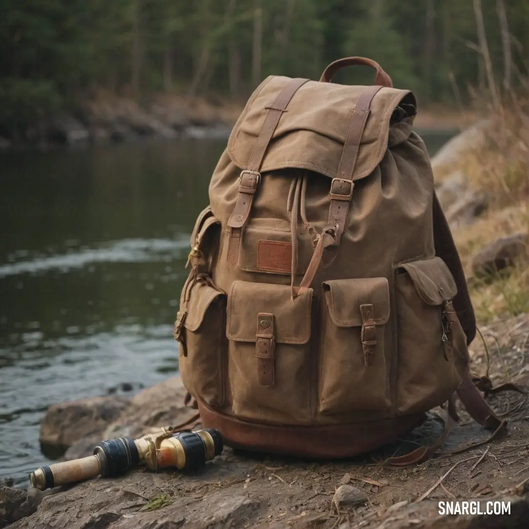 A fishing rod leans against a stylish backpack set atop a large rock. The serene river flows gracefully beside, framed by lush greenery and a sturdy tree providing a perfect backdrop to this calm scene.