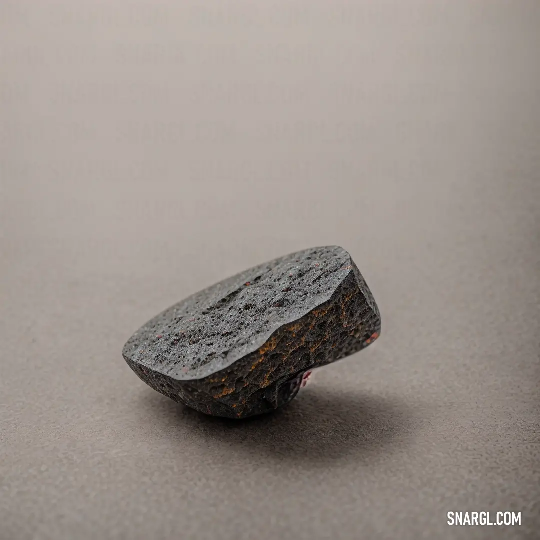Rock on top of a gray floor next to a white wall and a black object on the ground