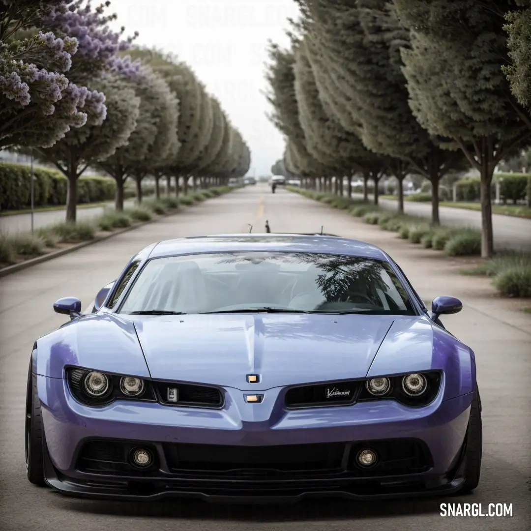 Blue sports car parked on a road lined with trees and bushes in front of a row of trees