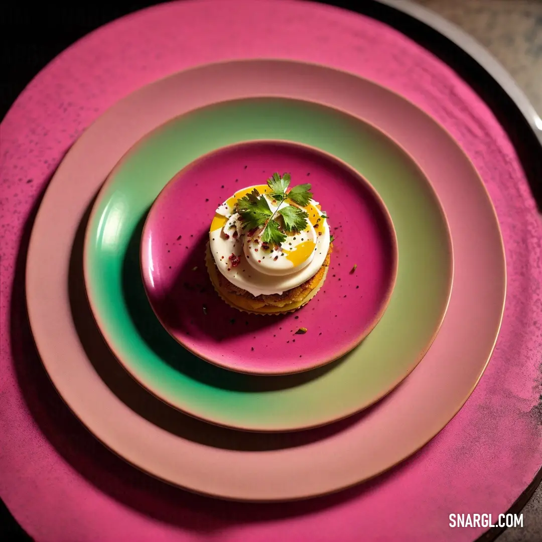 Plate with a small pastry on it on a table with a pink plate and a green plate