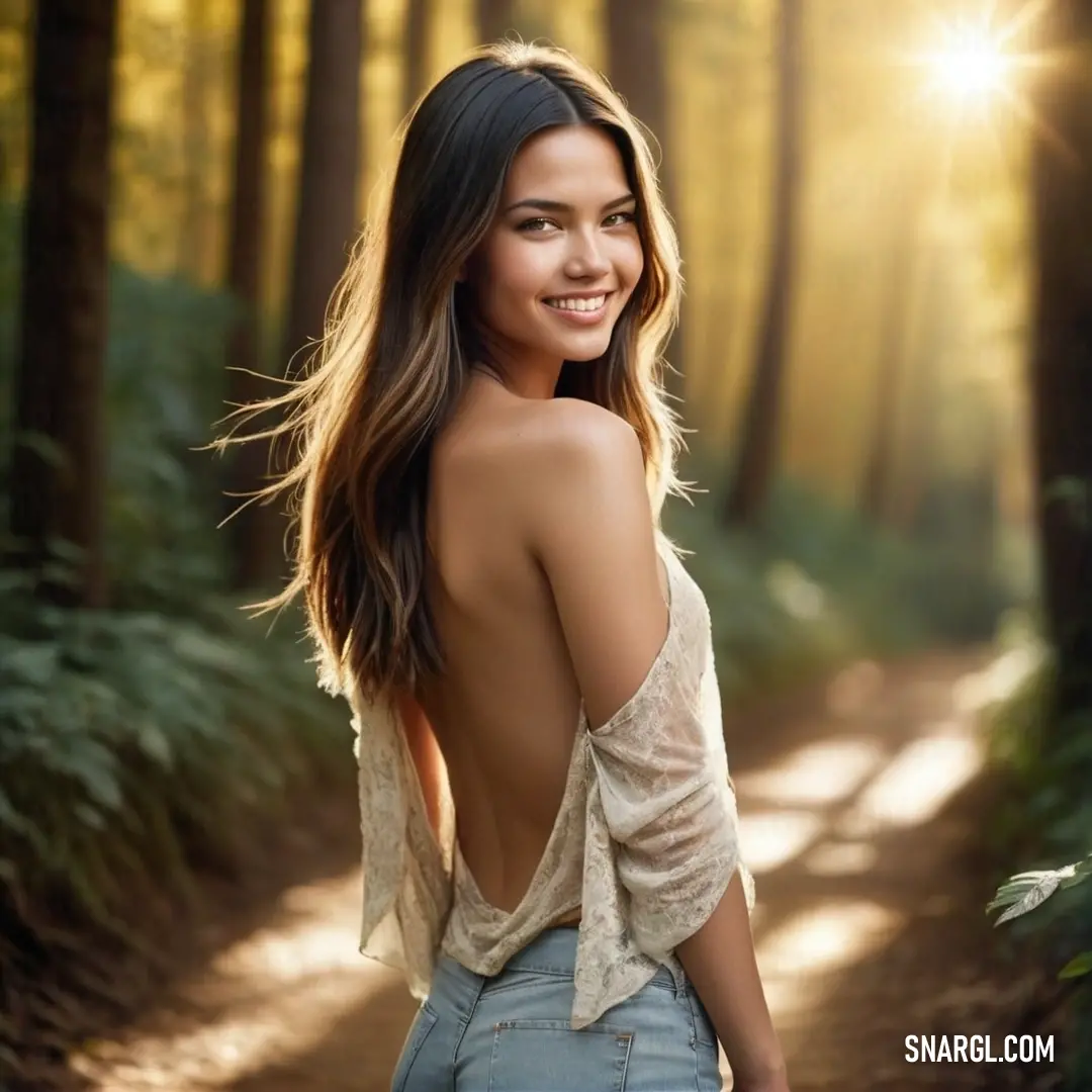 Woman standing in the woods with her back turned to the camera and smiling at the camera with sunlight streaming through the trees