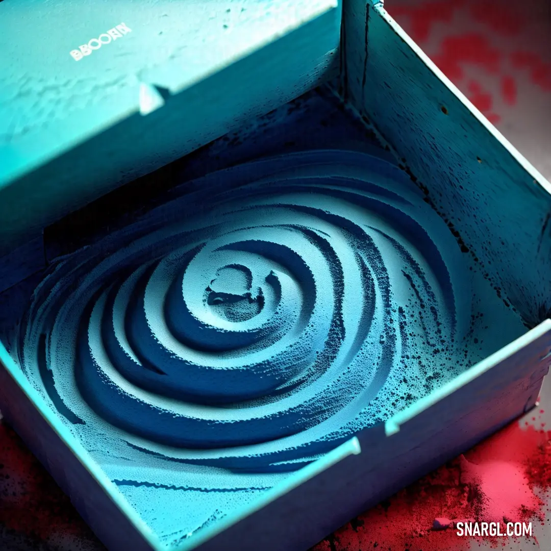 Blue box with a spiral design inside of it on a table with red paint on it