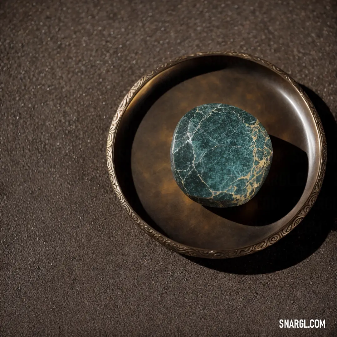 Small green rock in a bowl on a table top with a black background and a brown surface
