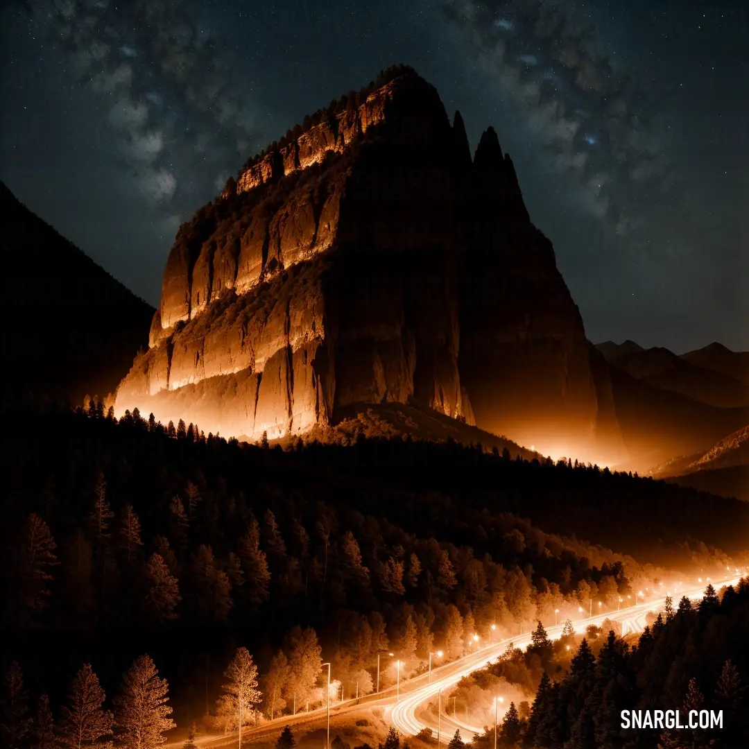 Mountain with a road going through it at night time with lights on it and a sky full of stars