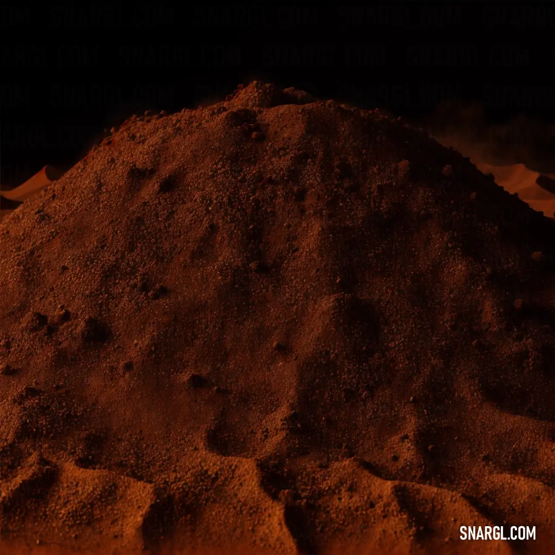 Pile of dirt on top of a sandy beach next to a dark sky with clouds in the background