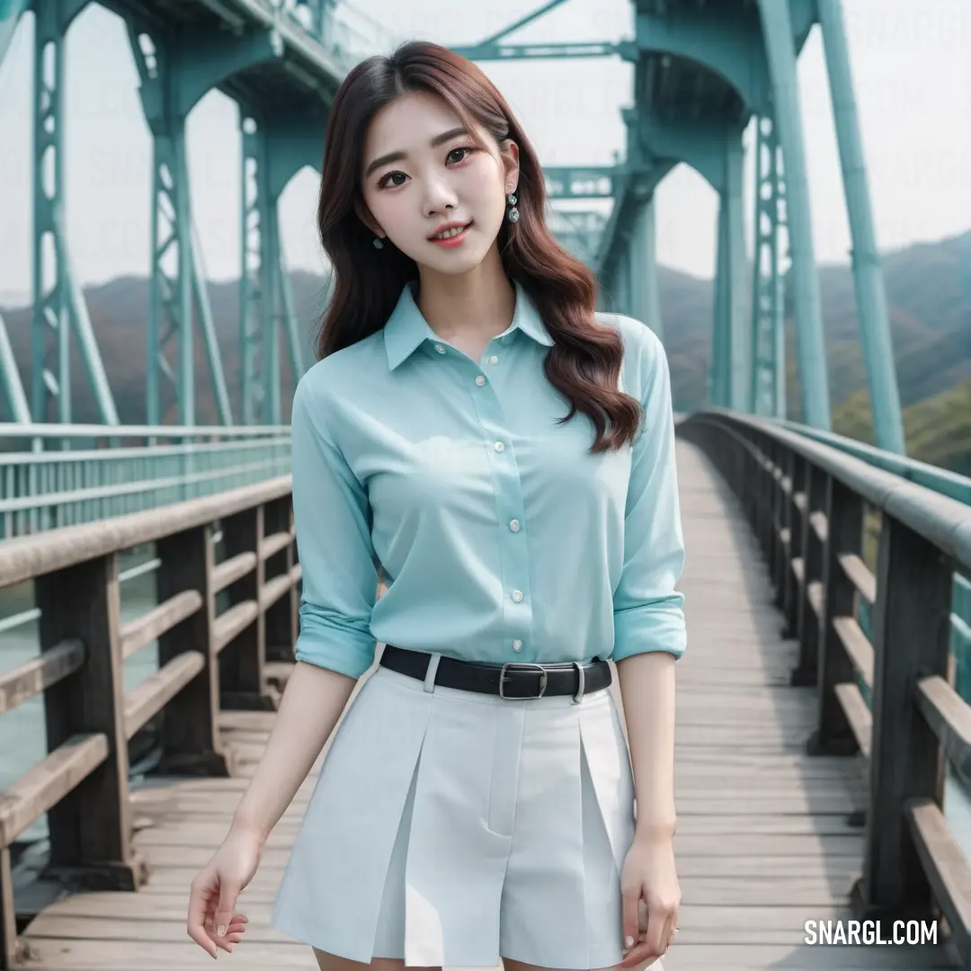 Woman standing on a bridge wearing a blue shirt and white skirt with a black belt around her waist