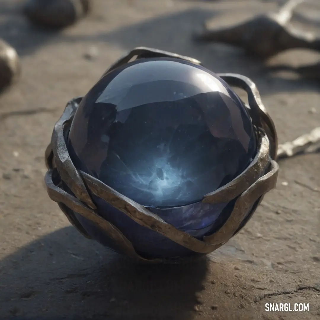 A metallic sphere with a decorative band rests on a rocky surface, surrounded by other weathered stones. A chain dangles from its side, adding a sense of weight and mystery to the scene. The rough textures of the rocks contrast with the smoothness of the 