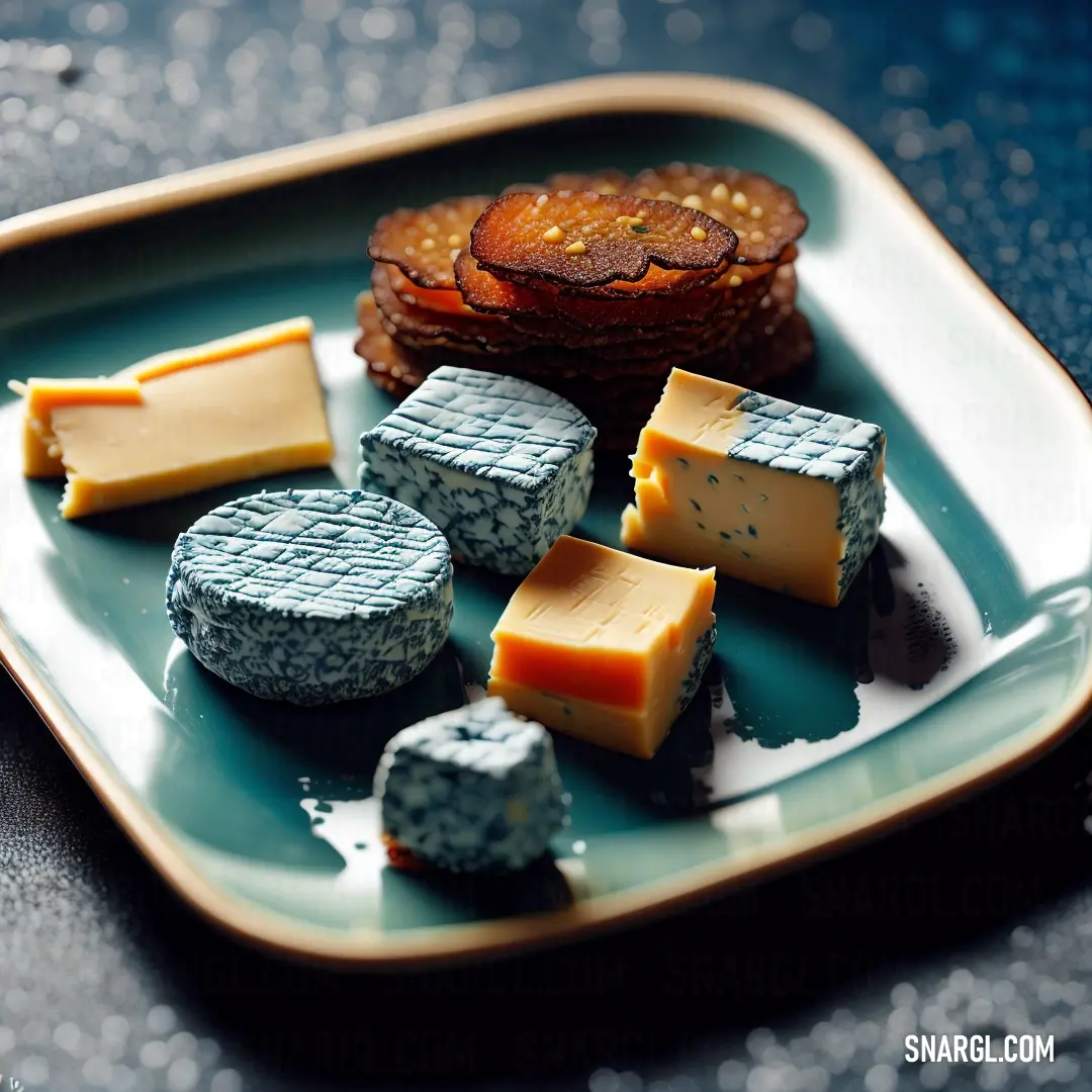 Plate of cheeses and crackers on a table top with a blue background