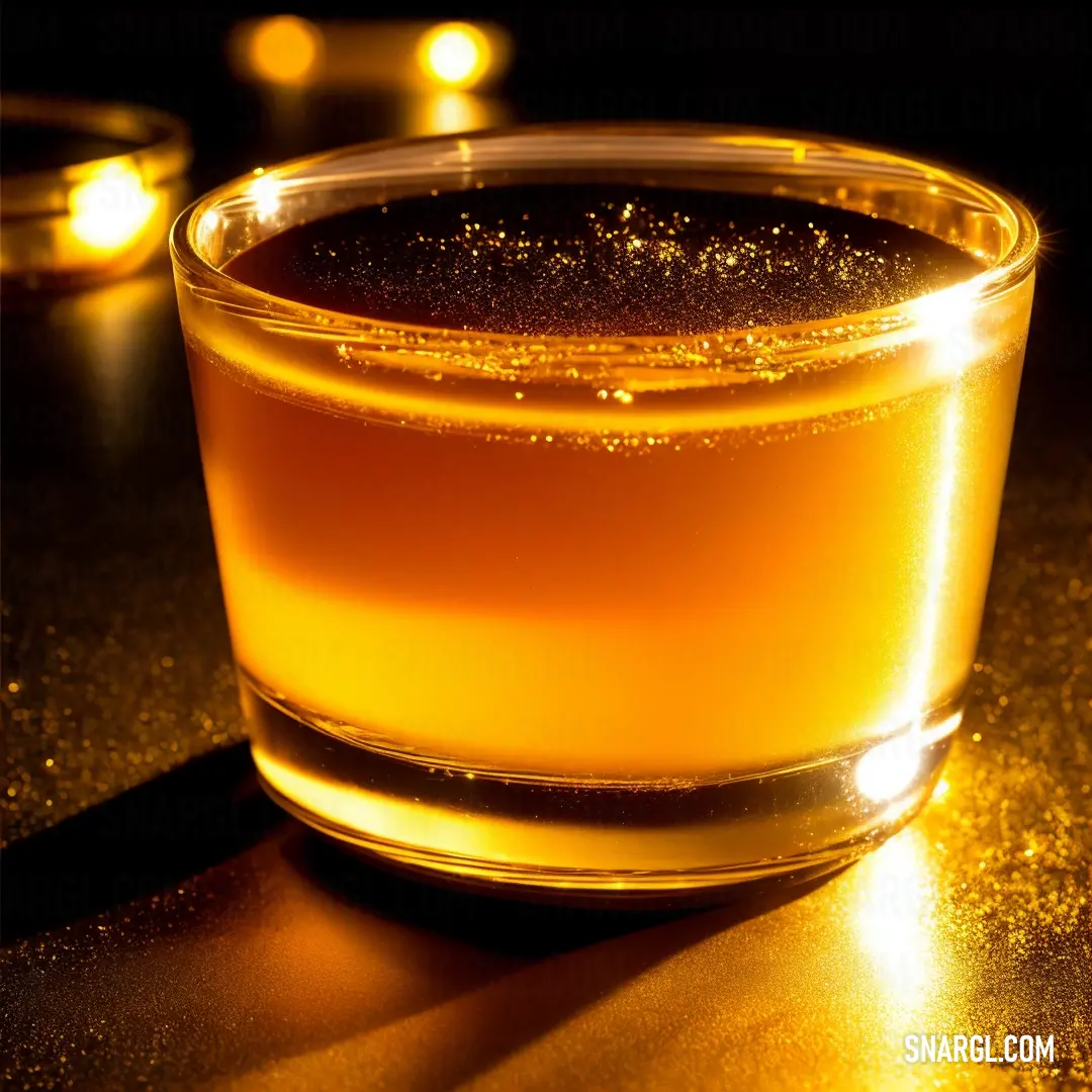 Glass of liquid on a table with candles in the background and a black background with a gold glitter effect