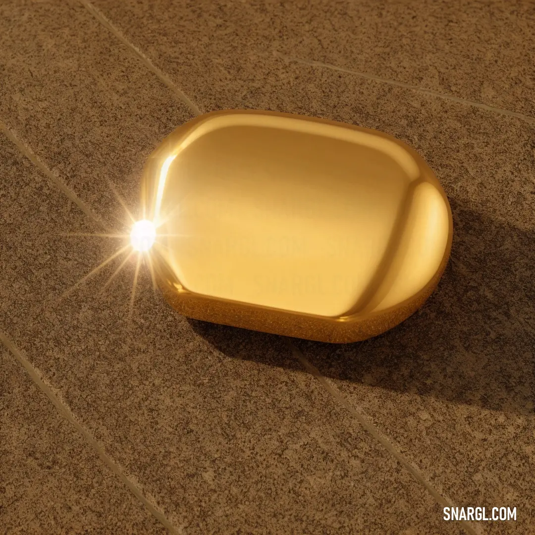 Shiny gold object on a brown surface with a light shining on it's side and a small square object on the floor