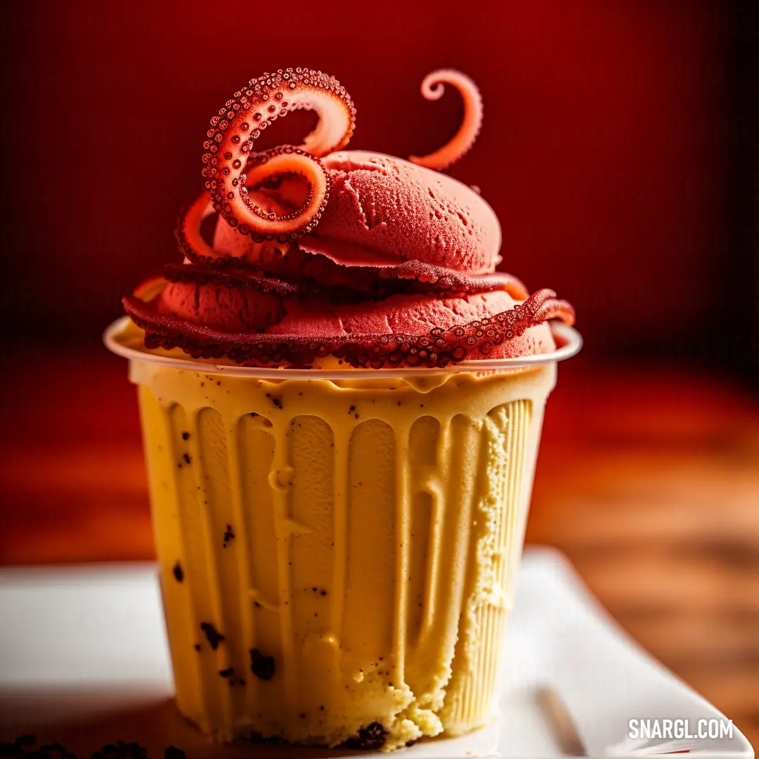 Cupcake with a red icing and an octopus on top of it on a plate on a table