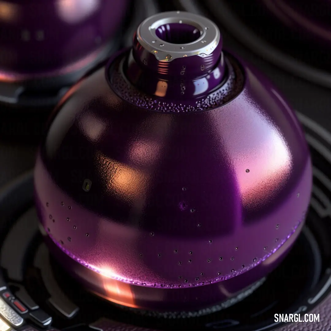Purple speaker with a silver knob on it's side and a black speaker in the background with a silver ring around it