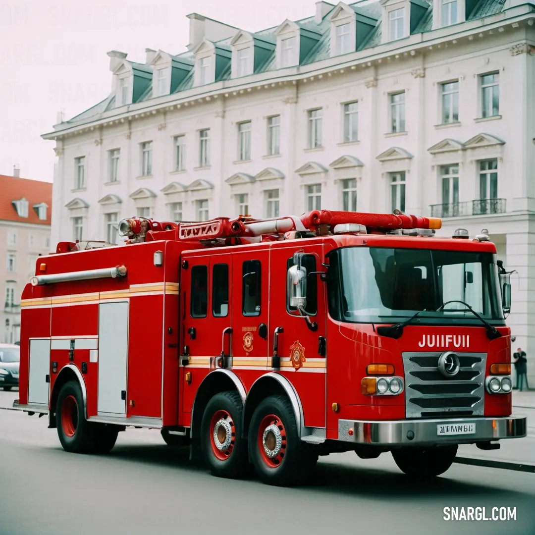 Red fire truck driving down a street next to a tall building with a clock on it's side. Example of CMYK 0,85,85,30 color.