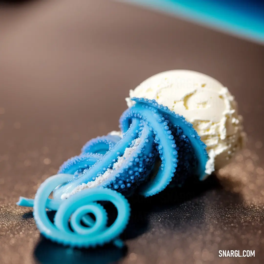 Blue and white object on a table next to a white ball of ice cream on top of it