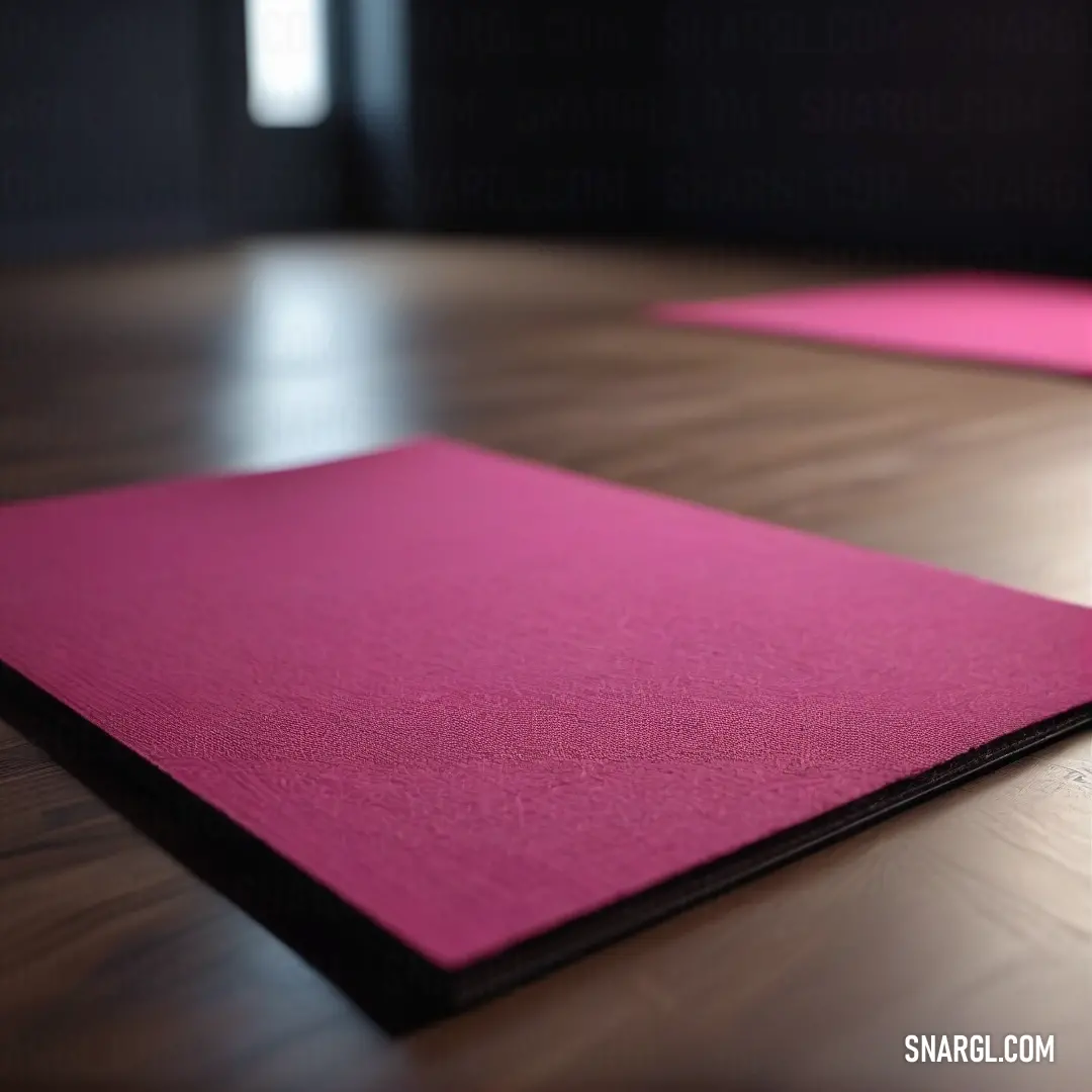 Cerise pink color example: Close up of a yoga mat on a wooden floor with a black background