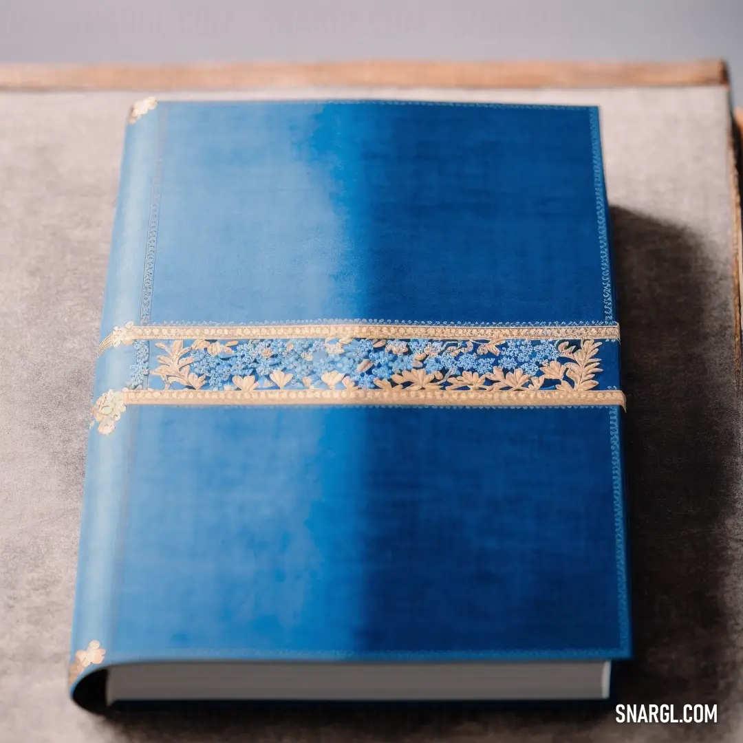 Blue book with a gold trim on a table top with a gray surface and a gray background