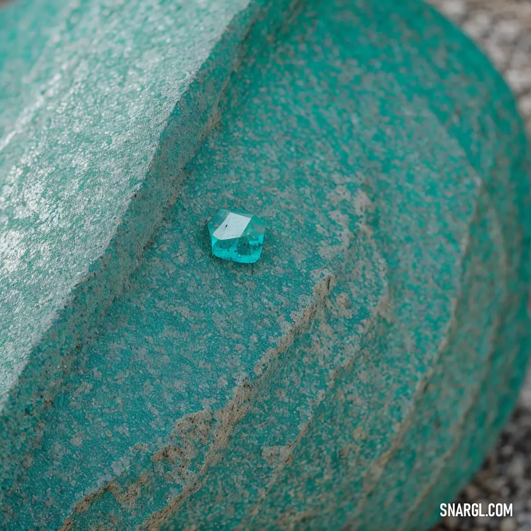 Small green object sitting on top of a green wall next to a sidewalk light on a sidewalk