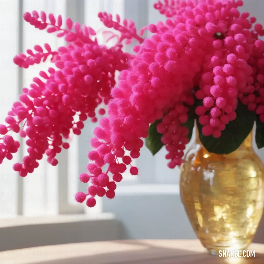 Vase with pink flowers in it on a table next to a window sill. Example of #DE3163 color.