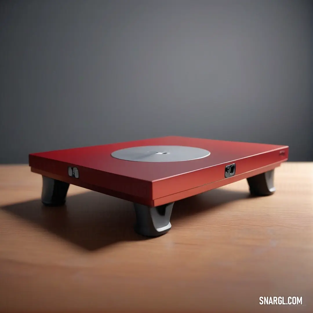 Chestnut color. Red table with a white disk on top of it on a wooden table top with a gray wall behind it