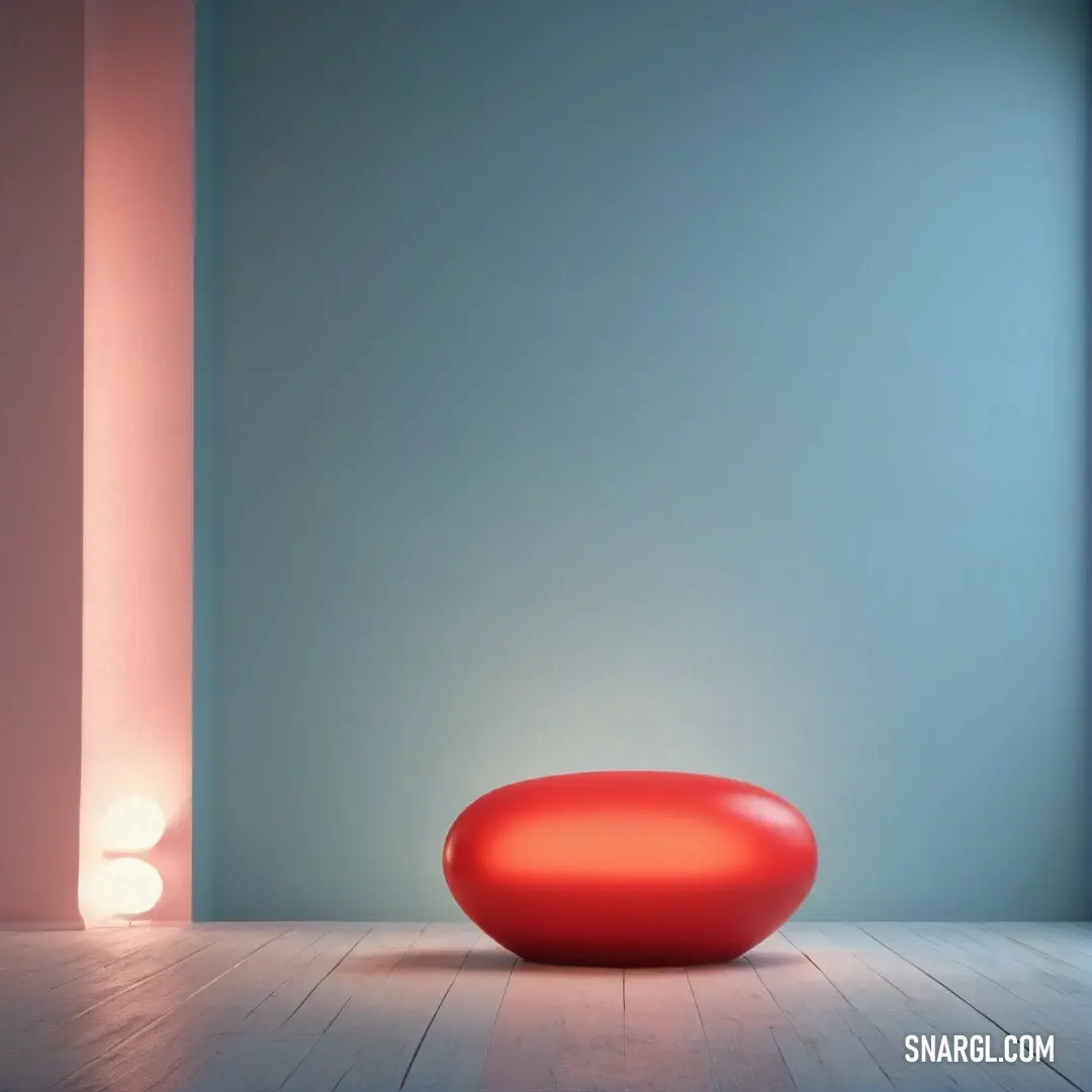 Red round object on a wooden floor in a room with a blue wall and a light on. Color RGB 227,66,52.