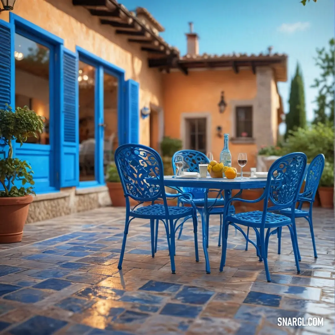 Blue table and chairs outside of a house with blue shutters and a blue door and windows. Example of CMYK 100,58,0,33 color.