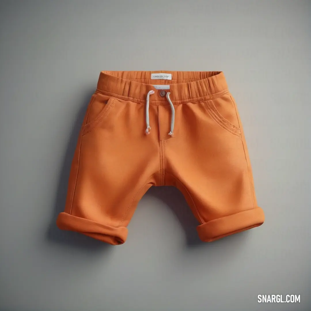 Pair of orange shorts with a white string on the bottom of the shorts is hanging on a wall. Example of Cocoa brown color.