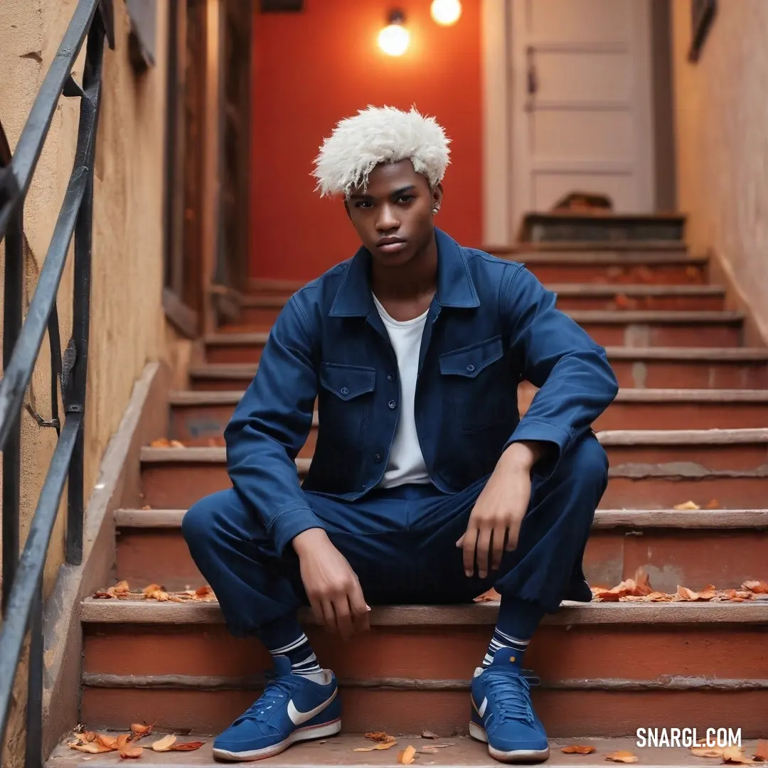 A striking image of a confident man with a unique white mohawk haircut sits on the steps of a classic building, dressed in casual blue jeans. His bold presence commands attention and reflects urban culture and individuality.