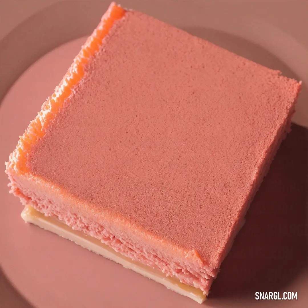 Pink cake with orange frosting on a plate with a fork and knife on the side of the plate