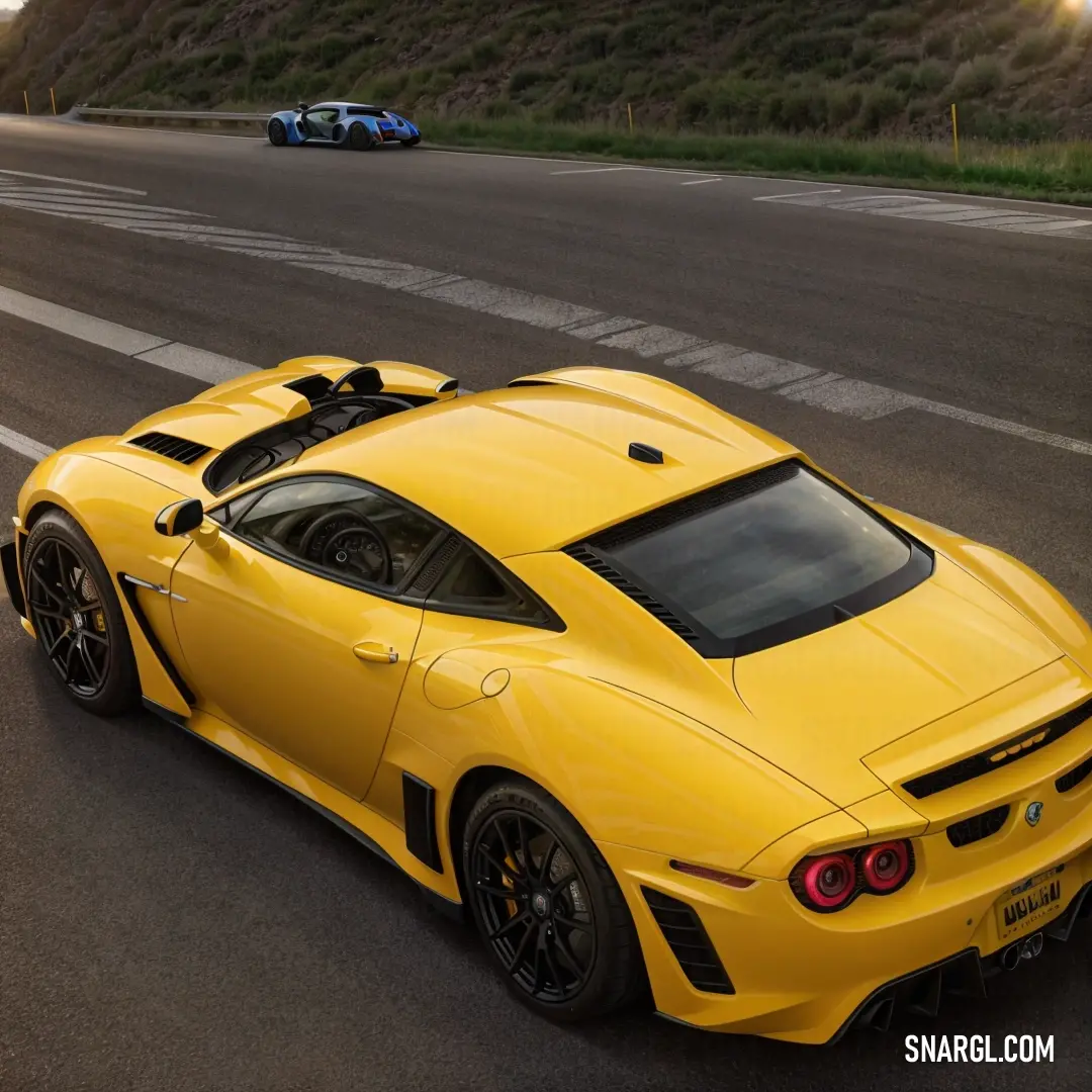 Yellow sports car driving down a road next to a hill side with a car behind it