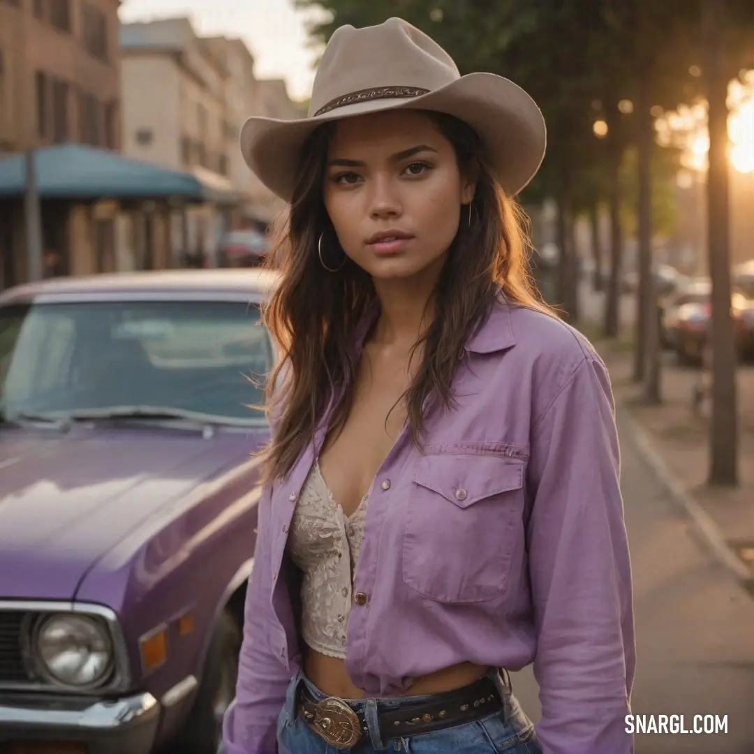 Woman in a cowboy hat standing next to a car on a street with a purple shirt and jeans