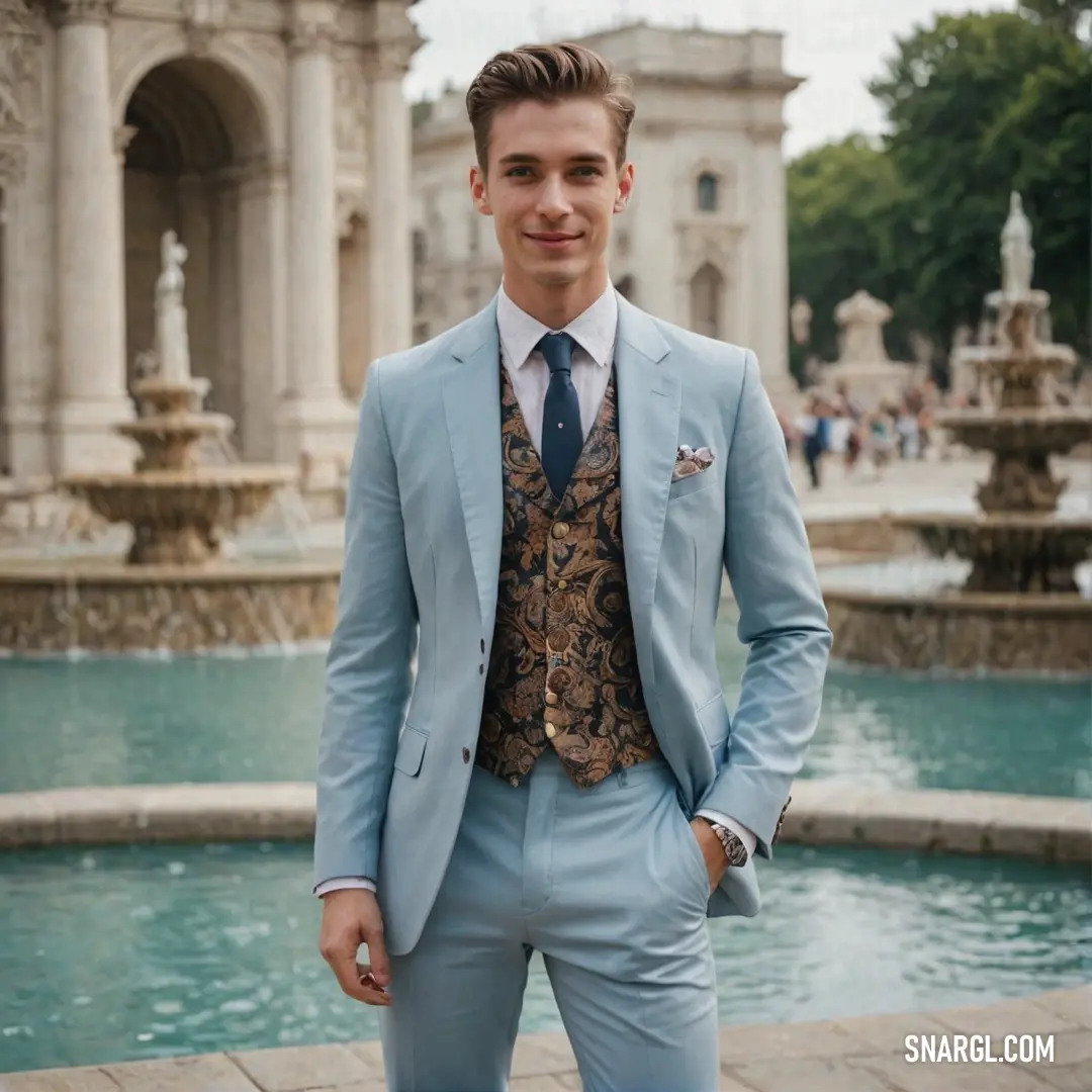 A man in a suit stands in front of a fountain in a park, the soothing flow of water behind him bringing a calm and serene atmosphere to the setting. A man in a suit stands by a fountain in a park, the water cascading gently in the background, adding a peaceful and refreshing ambiance to the scene.