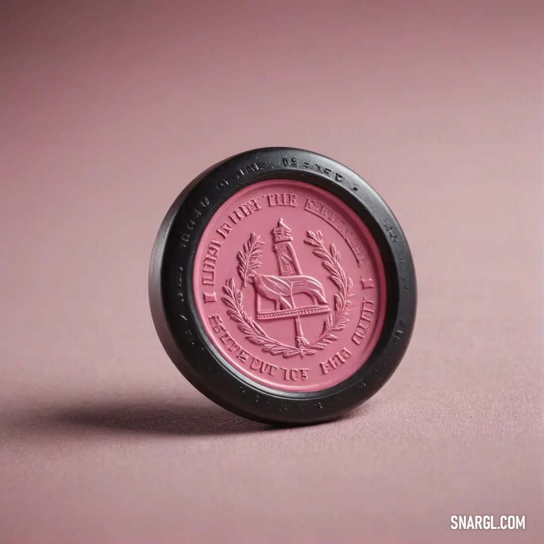 A pink and black coin with a sleek black lid resting on a soft pink surface. The contrast of these colors evokes a sense of depth and sophistication, with the unique design captivating the eye.